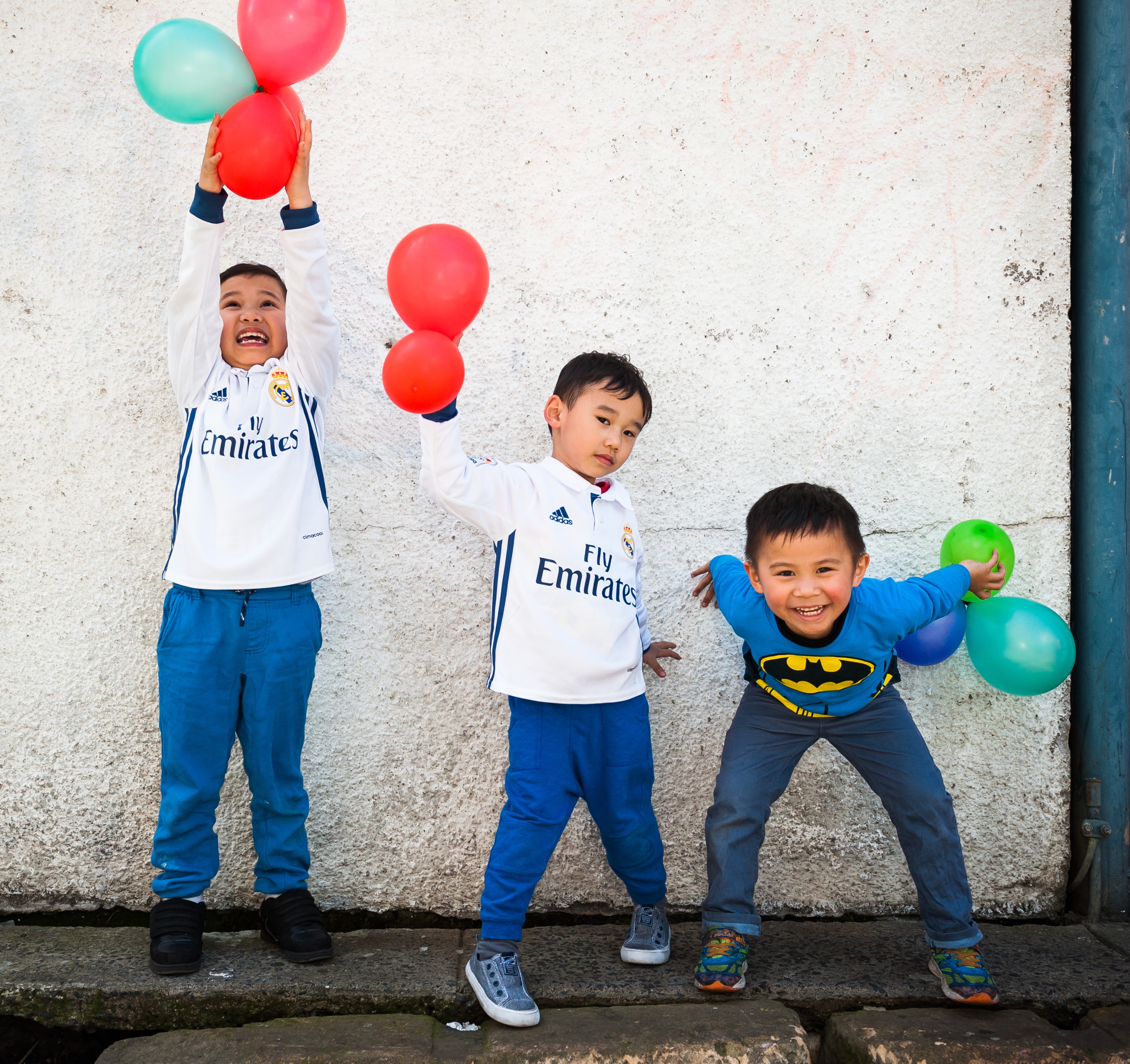  3 little boys fooling around with coloured balloons